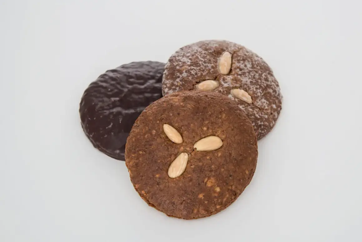 Drei runde Elisenlebkuchen, einer schokoladenüberzogen, die anderen mit Mandeln verziert. Beste Elisenlebkuchen für den Genuss.