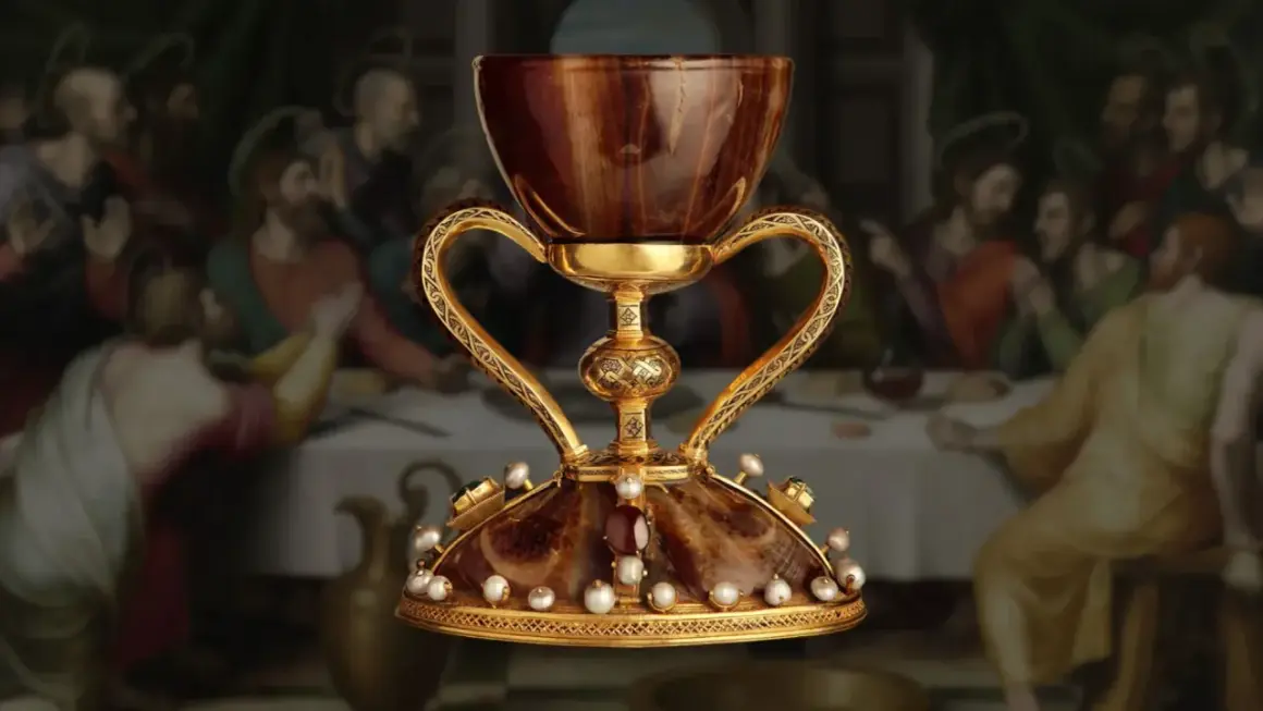 El cáliz dorado, adornado con perlas y gemas, evoca la búsqueda del santo grial donde está. Detrás, la Última Cena.