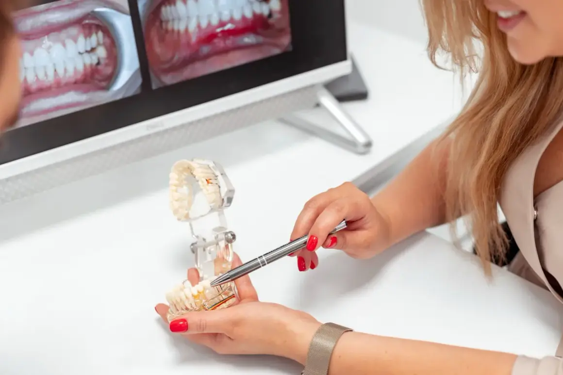 Dentystka omawia z pacjentem proces zakładania korony na zęba, używając modelu szczęki.