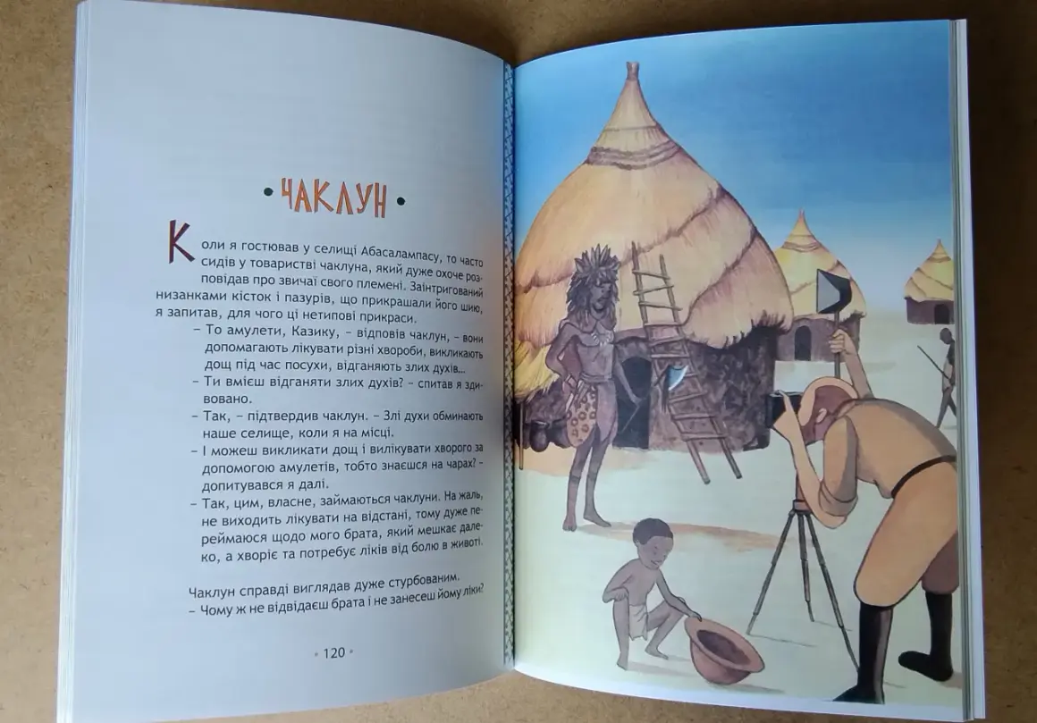 Afryka Kazika streszczenie: czarownik z plemienia Abasalamaps opowiada o swoich amuletach i mocy. Na ilustracji widać wioskę, czarownika i fotografa.