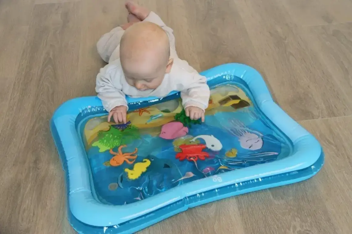Niemowlę bawi się na macie wodnej z morskimi stworzeniami. Mata wodna dla niemowlaka od kiedy? Od pierwszych miesięcy życia, wspiera rozwój.