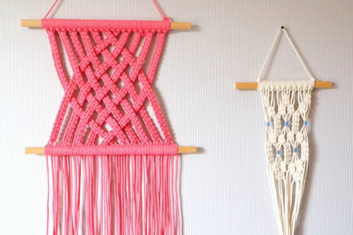 Deux tentures murales en macramé : une rose vif avec un motif croisé, et une écru avec des perles bleues. Idéal pour un tuto macramé mural.