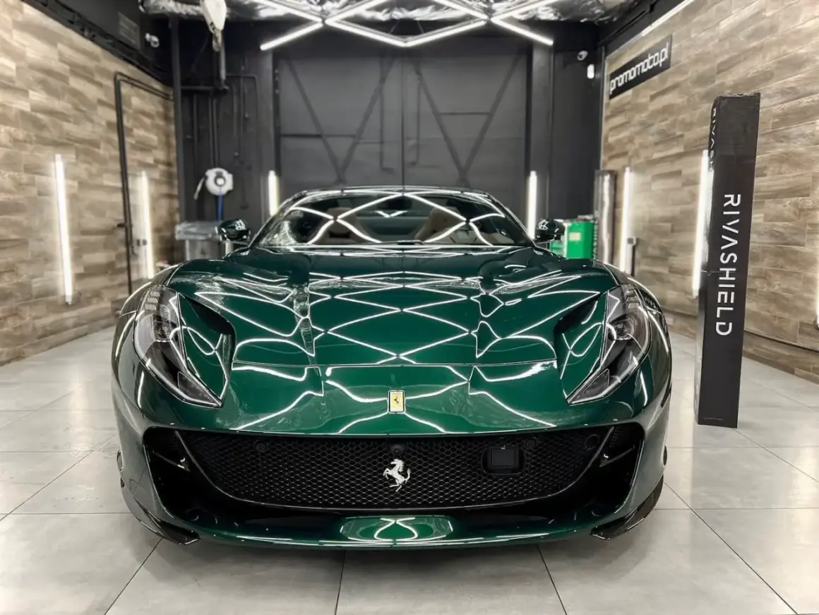 Zielone Ferrari po nałożeniu ceramiki na auto. Lśniący lakier odbija światła studia detailingowego.