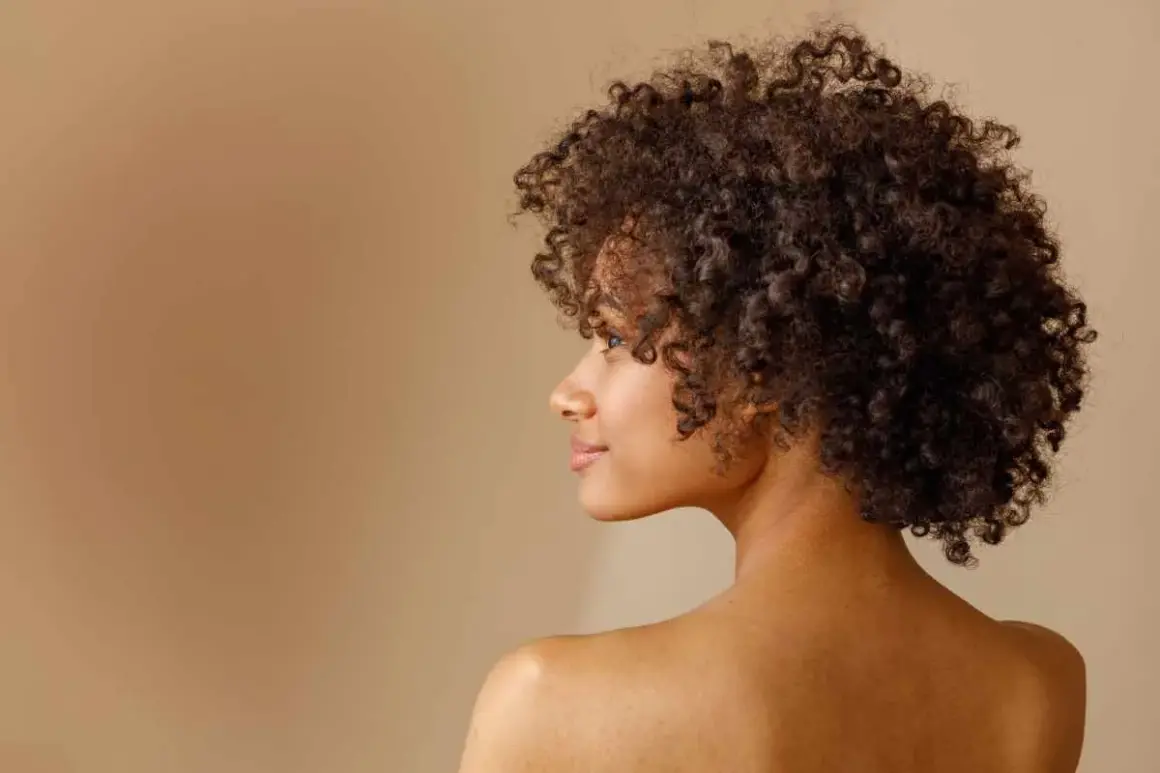 Perfil de una mujer con un espectacular pelo afro, rizos definidos y un rostro sereno.