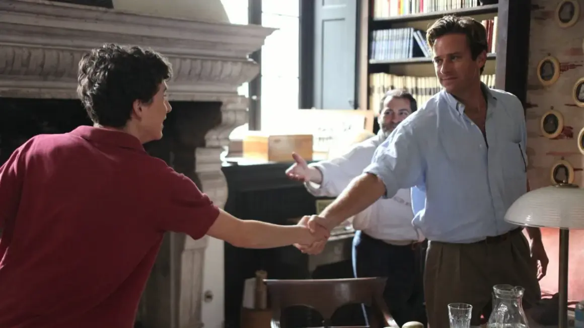 Elio und Oliver schütteln sich die Hände, ein Moment, der an "Call Me By Your Name 2" erinnert. Ein Mann im Hintergrund lächelt.