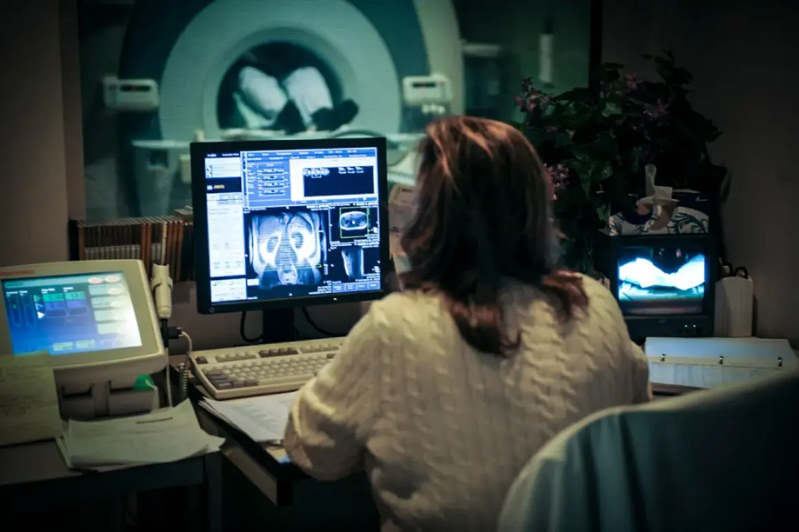 Kobieta analizuje obrazy z rezonansu magnetycznego na monitorze w pracowni medycznej.