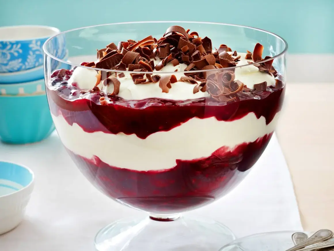 Schichtdessert mit Kirschen und einer luftigen Creme aus Mascarpone, garniert mit Schokoladenlocken.