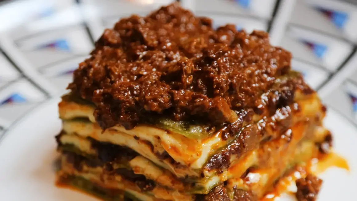 Una porzione di lasagne al ragù, stratificata con pasta, besciamella e un ricco ragù di carne.