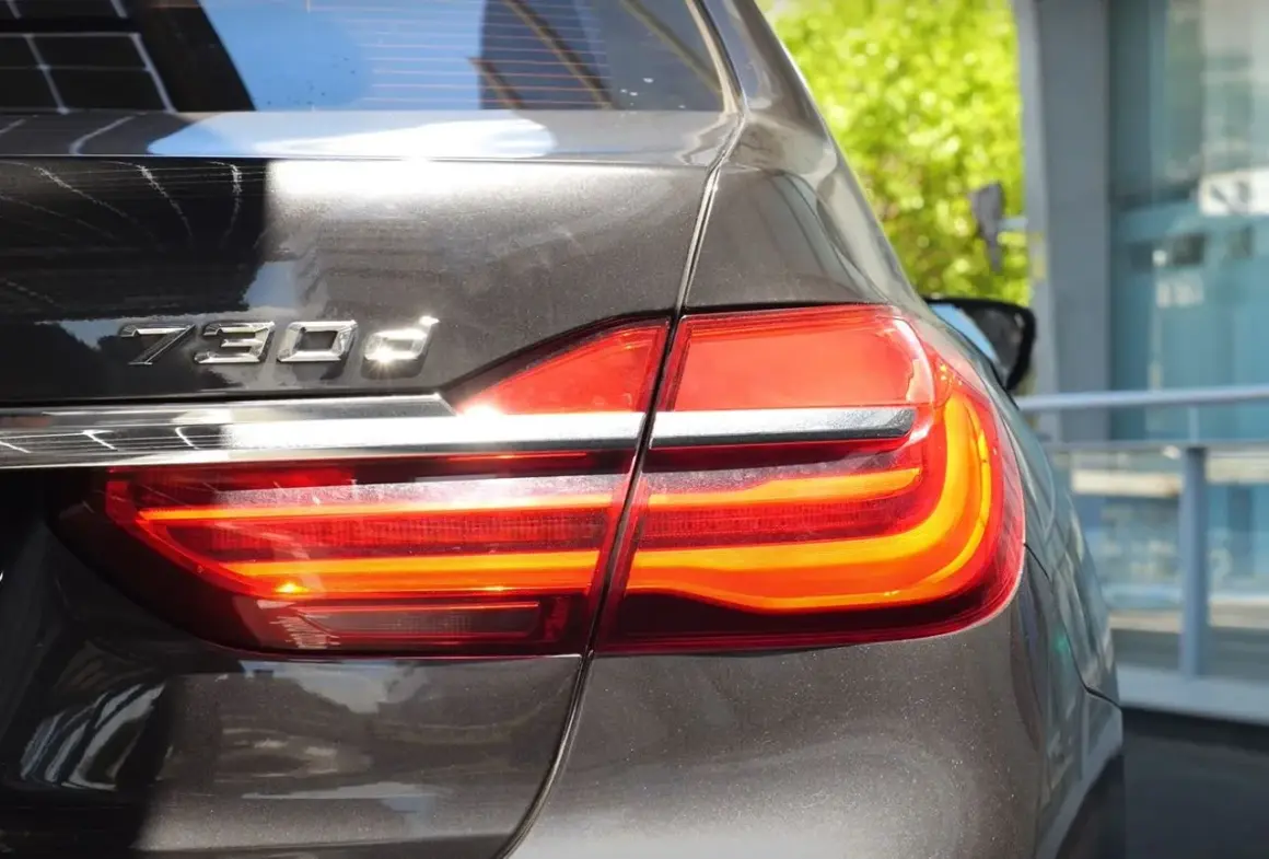 Tylna część lśniącego BMW 730d z włączonymi światłami stopu.