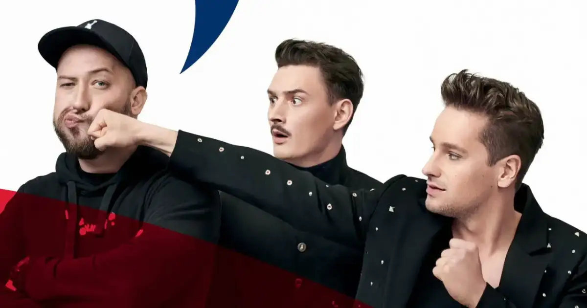 Trzech mężczyzn w czarnych strojach, jeden w czapce z daszkiem, przygotowuje się do męskiego grania. Orkiestra czeka na początek.