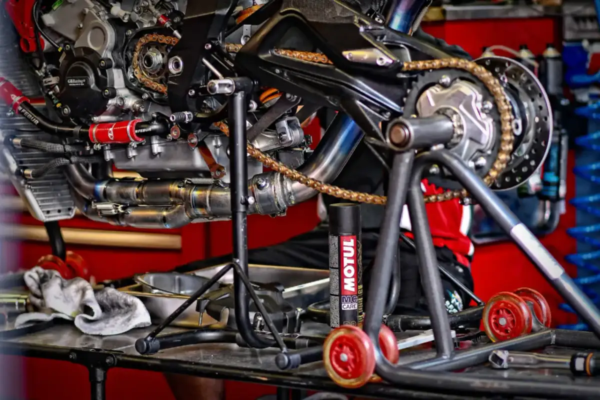 Motocykl na stojaku, gotowy do smarowania łańcucha. Puszka smaru Motul obok.