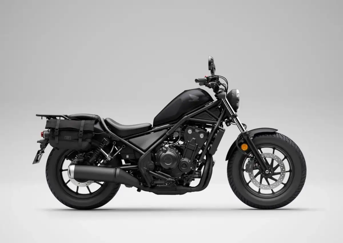Czarny motocykl Honda Rebel 500 z sakwami, gotowy na podróż. Jego prędkość maksymalna pozwala na swobodne pokonywanie tras.