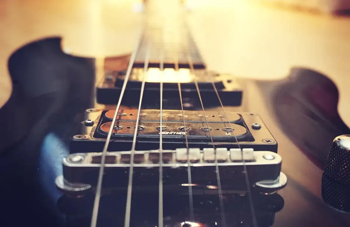 Zbliżenie na czarną gitarę elektryczną, jej struny i przetworniki. Czy to brzmienie mainstream co to?