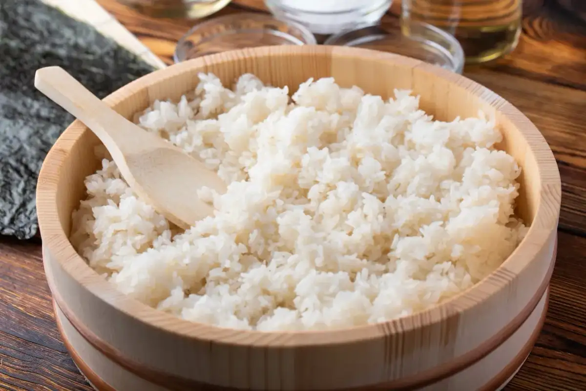 Idealny ryż do sushi, gotowy do przygotowania. Drewniana miska i łyżka sugerują tradycyjny sposób na to, jak ugotować ryż do sushi.