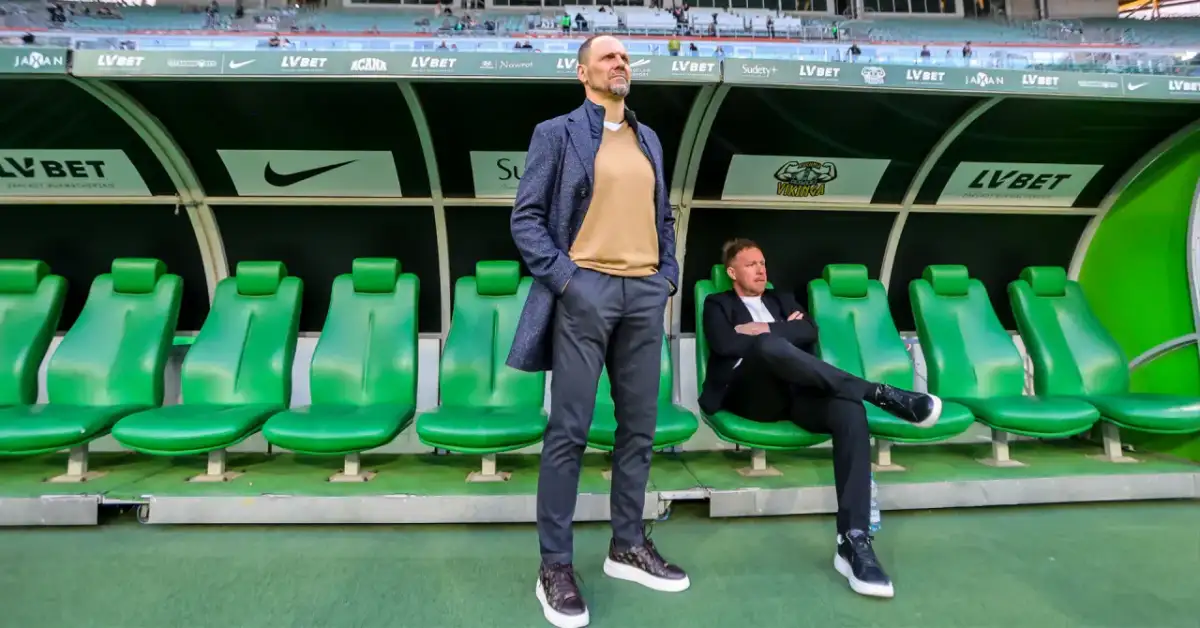 Trener Śląska Wrocław Ivan Djurdjevic stoi na tle zielonych siedzeń rezerwowych.