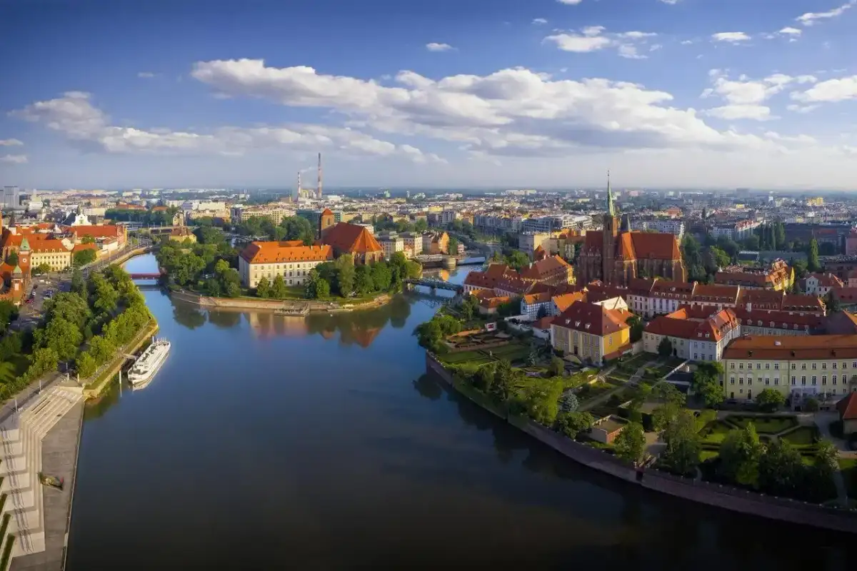 Majówka we Wrocławiu: malowniczy widok na Ostrów Tumski z rzeką i zabytkowymi budynkami.
