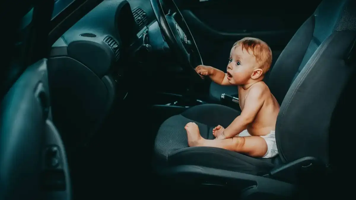 Maluch siedzi za kierownicą, jakby zastanawiał się, od kiedy dziecko może jeździć z przodu.