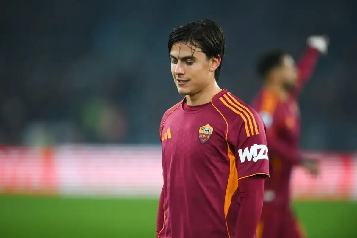 Piłkarz AS Roma w bordowej koszulce z pomarańczowymi pasami, gotowy do gry przeciwko Atalancie.