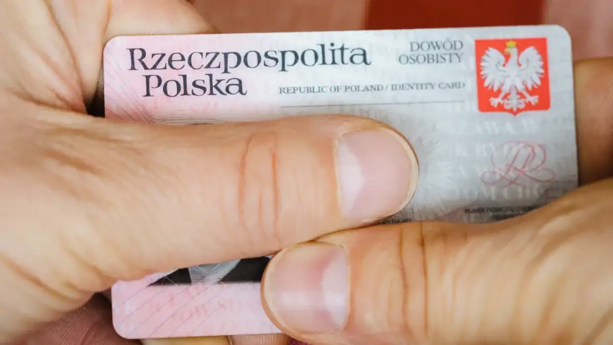 Dłonie trzymają polski dowód osobisty. Widoczny jest numer dowodu osobistego.