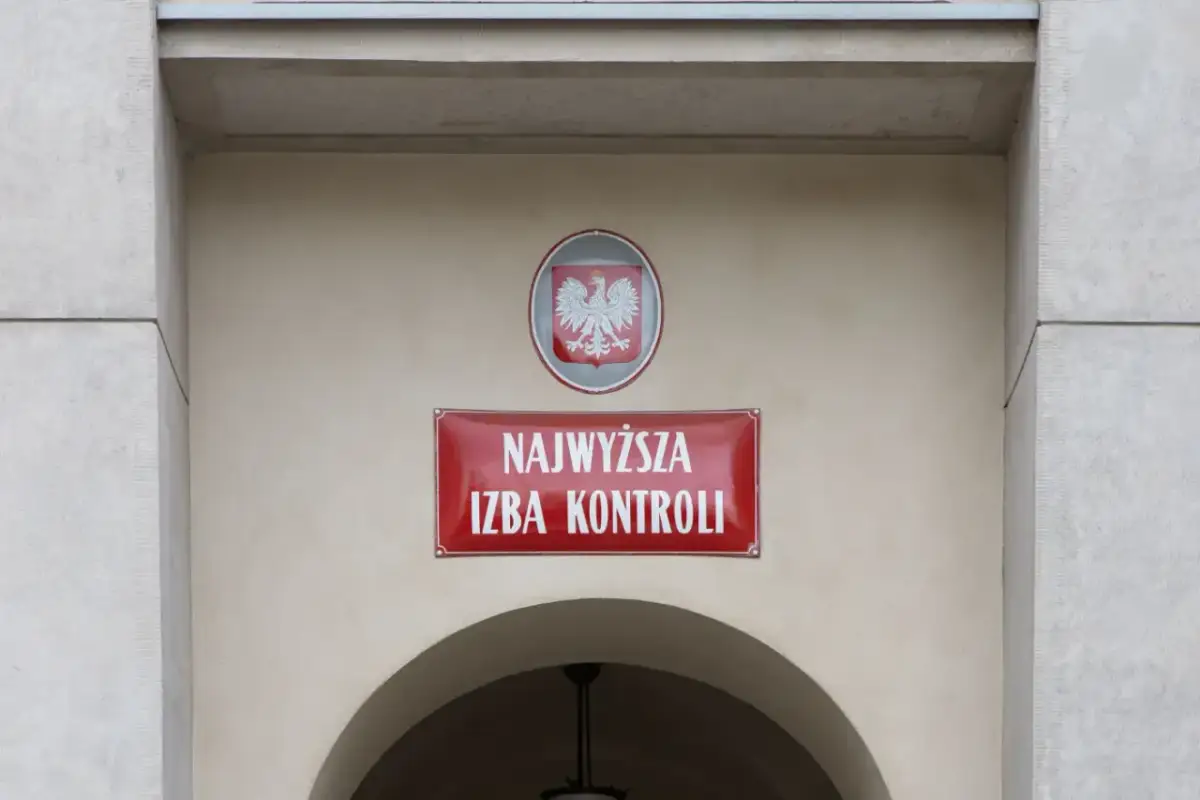 Tablica z napisem "Najwyższa Izba Kontroli" i godłem Polski na jasnym budynku.
