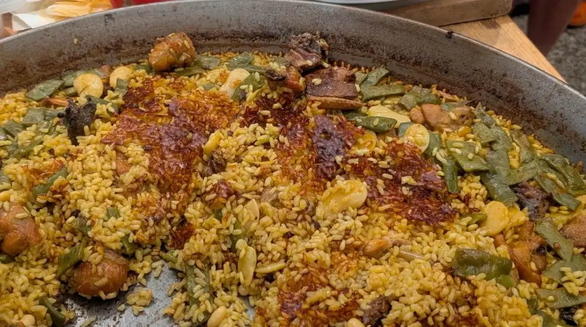 Paella de carne recién hecha, con arroz dorado, trozos de carne tierna, judías verdes y un delicioso socarrat crujiente.
