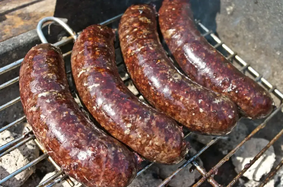 Cztery kaszanki na grillu. Zastanawiasz się, czy kaszankę można mrozić? Tak, można ją zamrozić, by cieszyć się smakiem później.