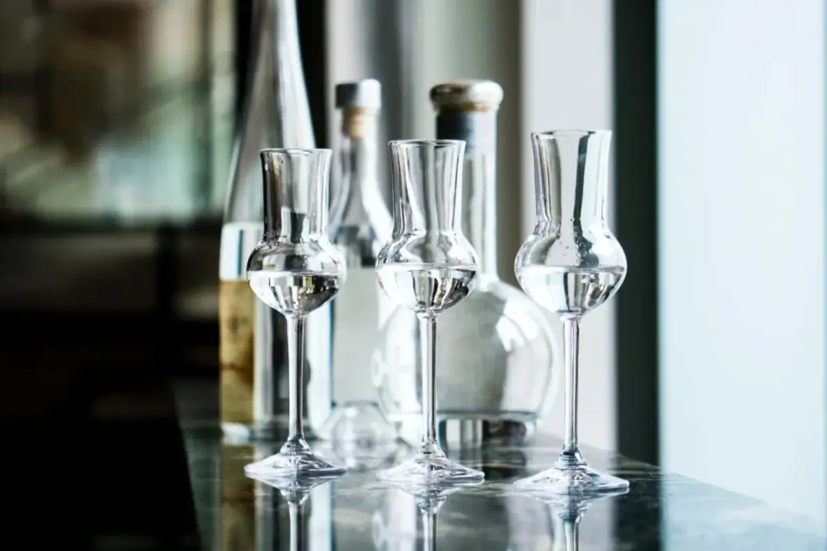 Trzy kieliszki z przezroczystym płynem, idealne do degustacji grappy. Co to jest grappa? To włoski destylat z wytłoków winogron.