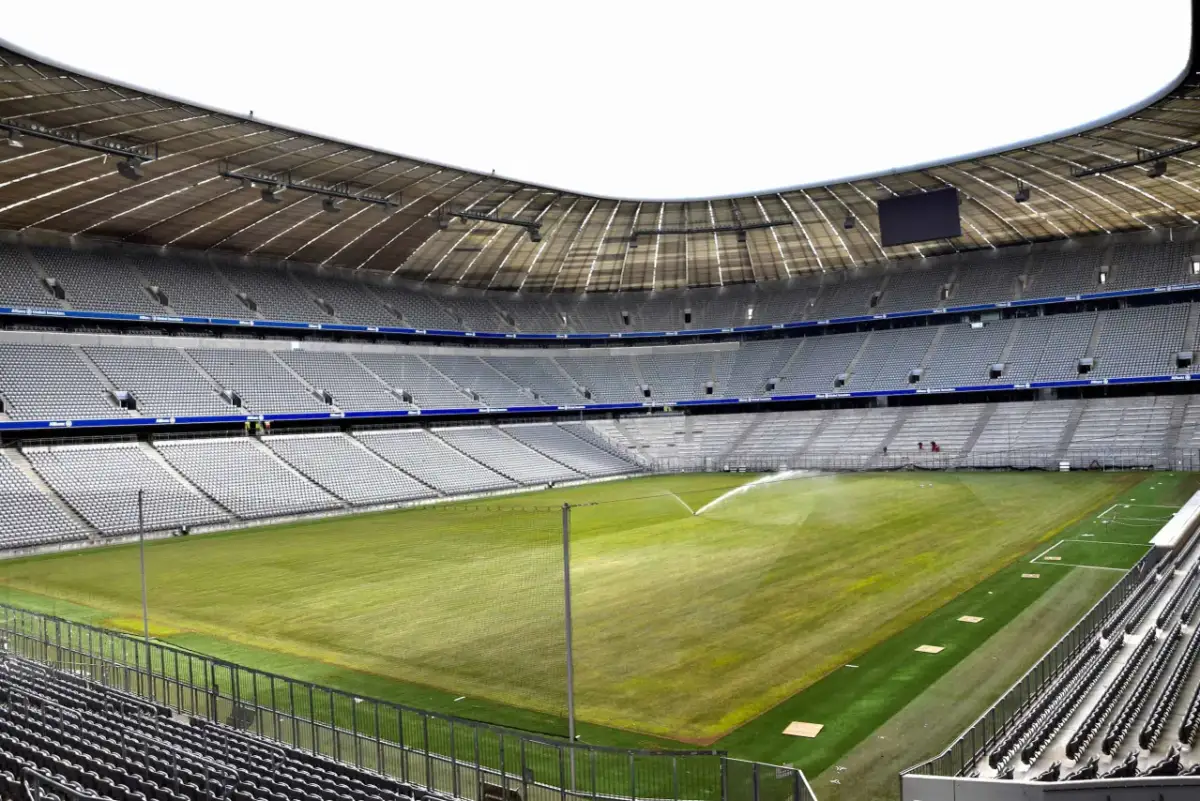Pusta Allianz Arena, z zieloną murawą i trybunami czekającymi na kibiców.