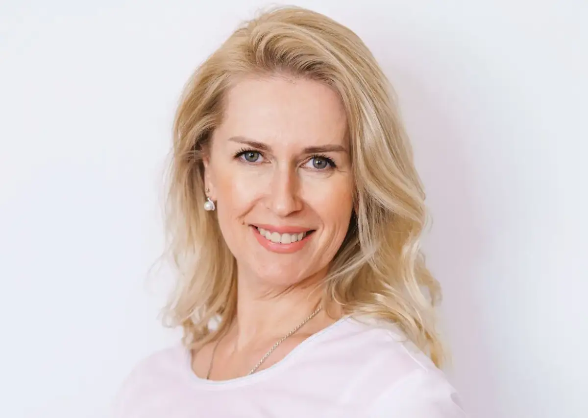 Uśmiechnięta blondynka po czterdziestce z fryzurą dodającą objętości cienkim włosom.