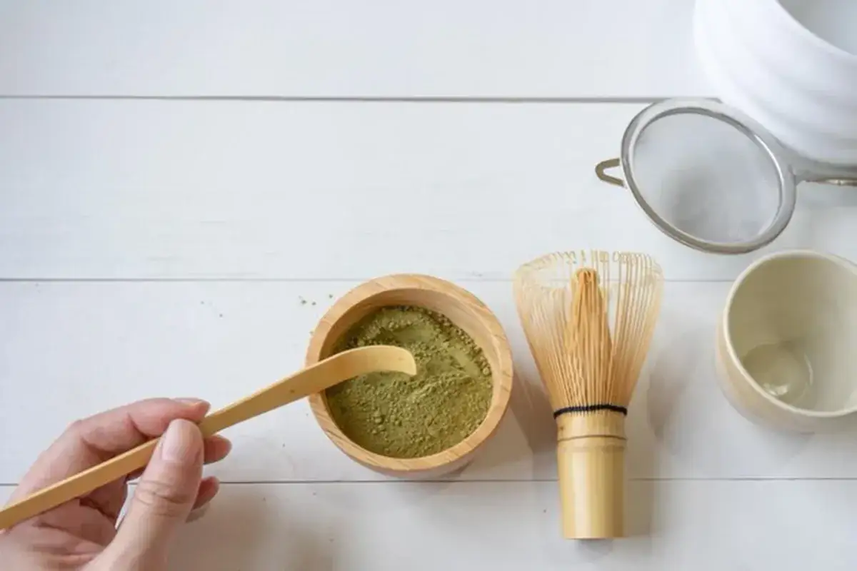 Akcesoria do przygotowania matcha: miseczka z zielonym proszkiem, bambusowa miotełka i łyżeczka. Gdzie kupić matcha?