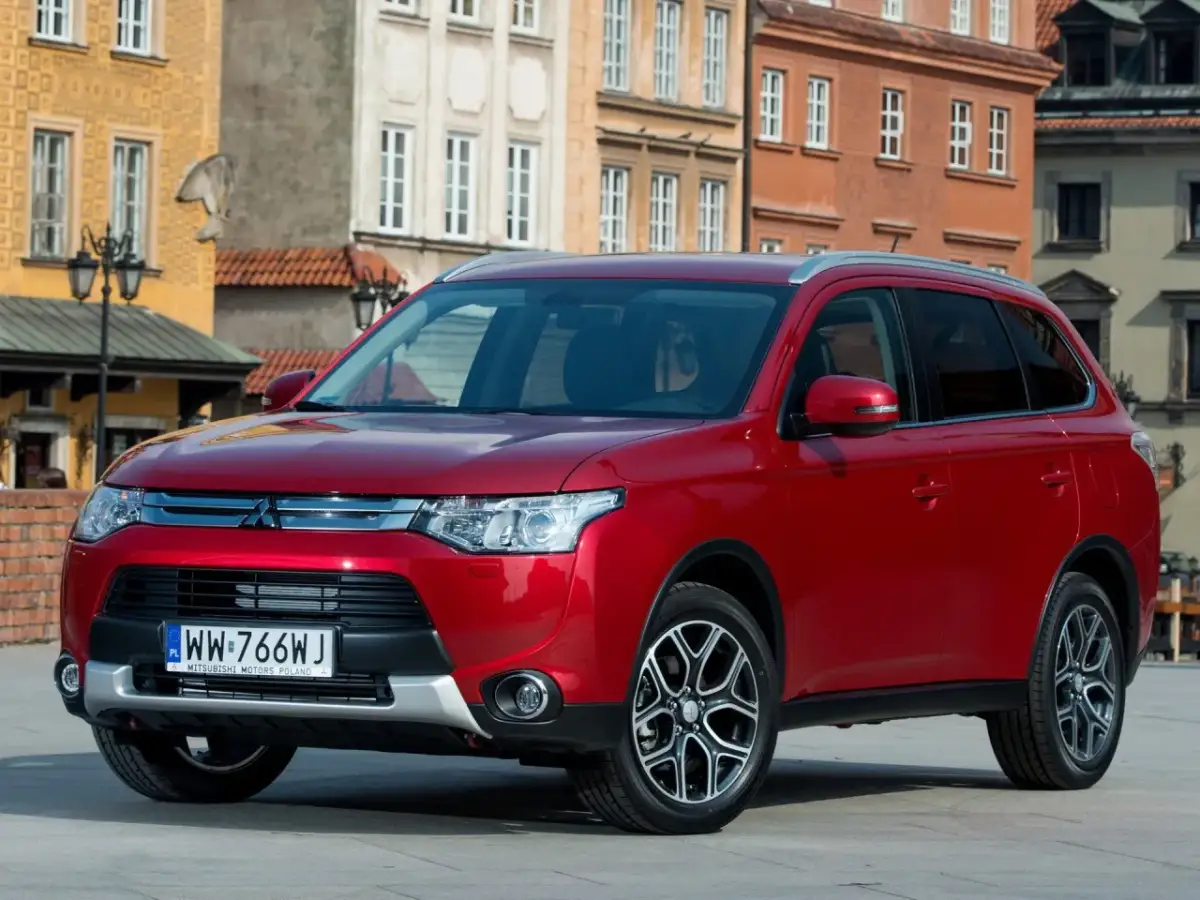 Czerwony Mitsubishi Outlander na tle kamienic. Wiele osób szuka mitsubishi outlander opinie przed zakupem.