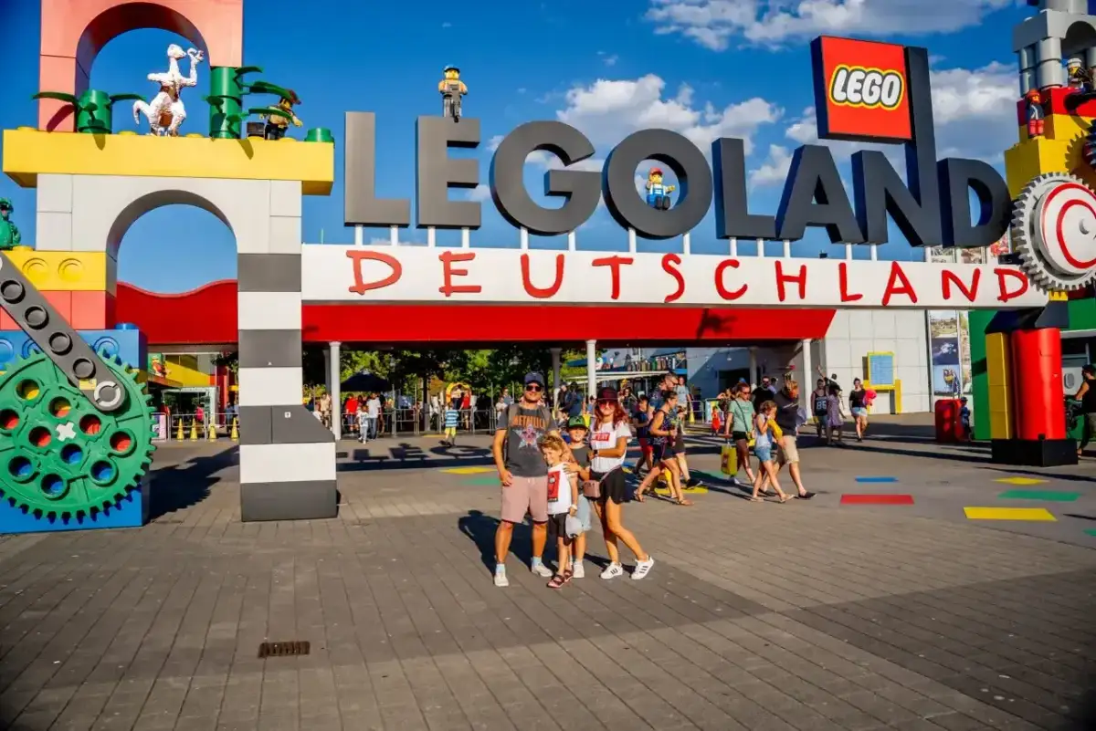 Rodzina pozuje przed wejściem do Lego Land Deutschland. Kolorowe klocki i wielkie logo zapraszają do świata zabawy.