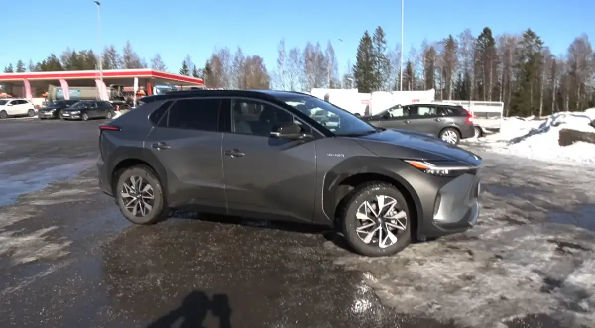 Szary Toyota bz4x test na tle stacji benzynowej i zaśnieżonego terenu.