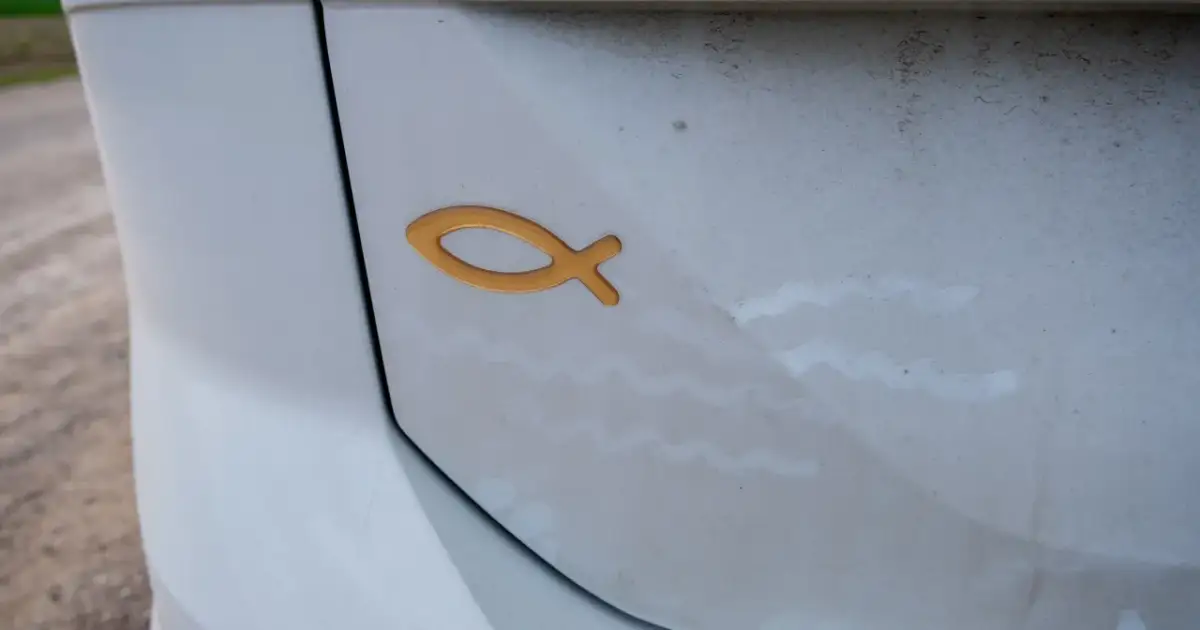 Złoty symbol ryby na białym samochodzie. To chrześcijański znak, który oznacza "Jezus Chrystus, Syn Boży, Zbawiciel".