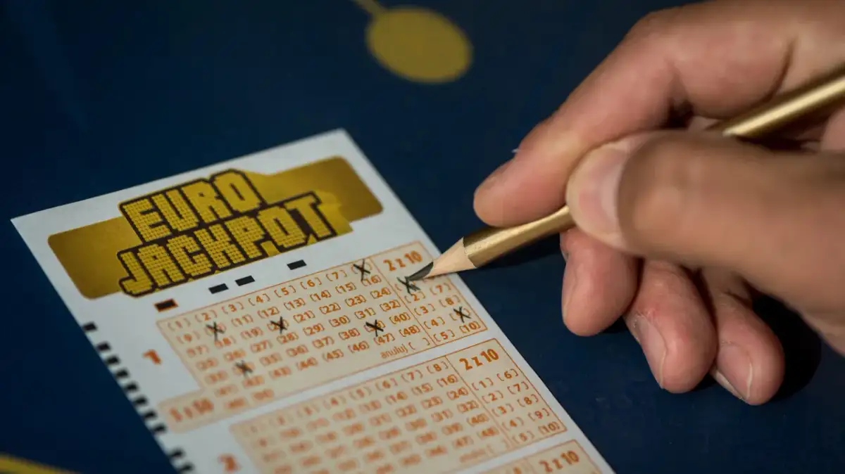 Dłoń z ołówkiem zaznacza liczby na kuponie Eurojackpot. Zastanawiasz się eurojackpot do której godziny? Sprawdź, zanim będzie za późno!