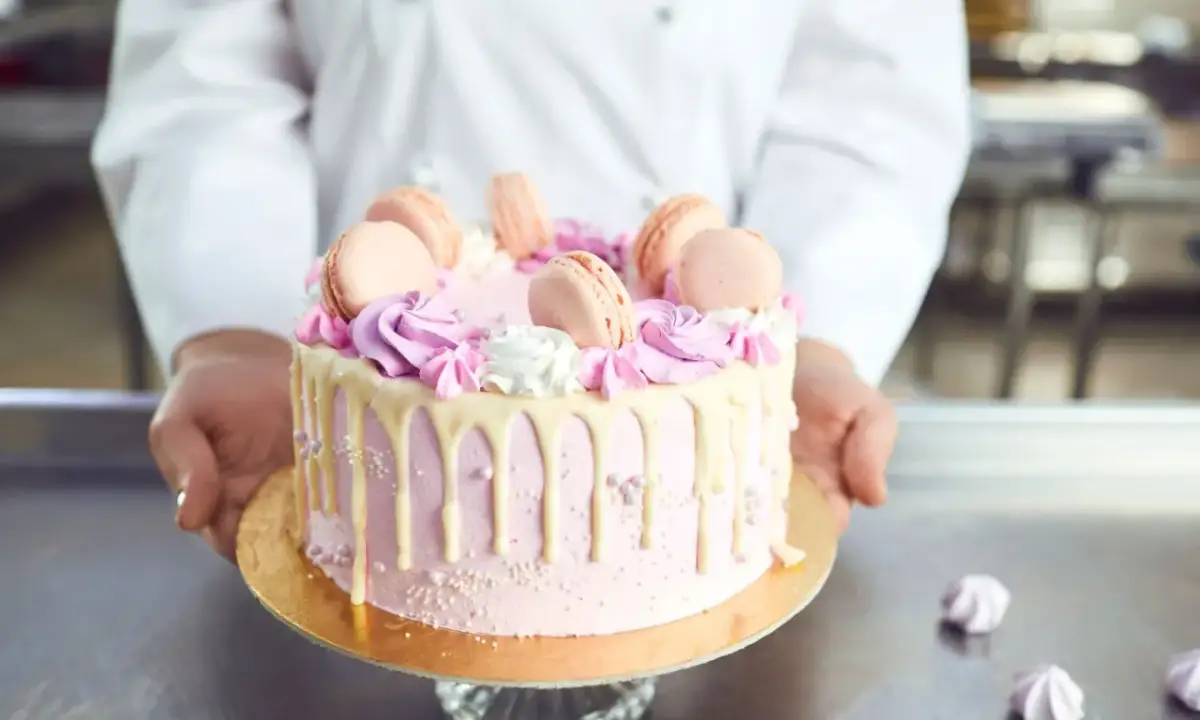 Różowy tort z makaronikami i kremem. Idealne ozdoby do tortu znajdziesz w cukierni.