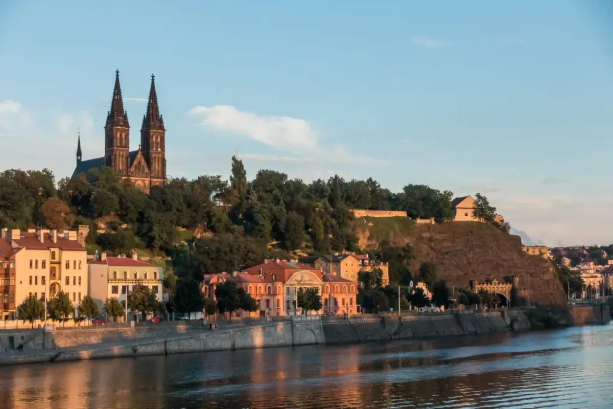 Wyszehrad góruje nad Wełtawą, z dominującą bazyliką i zielonymi wzgórzami.