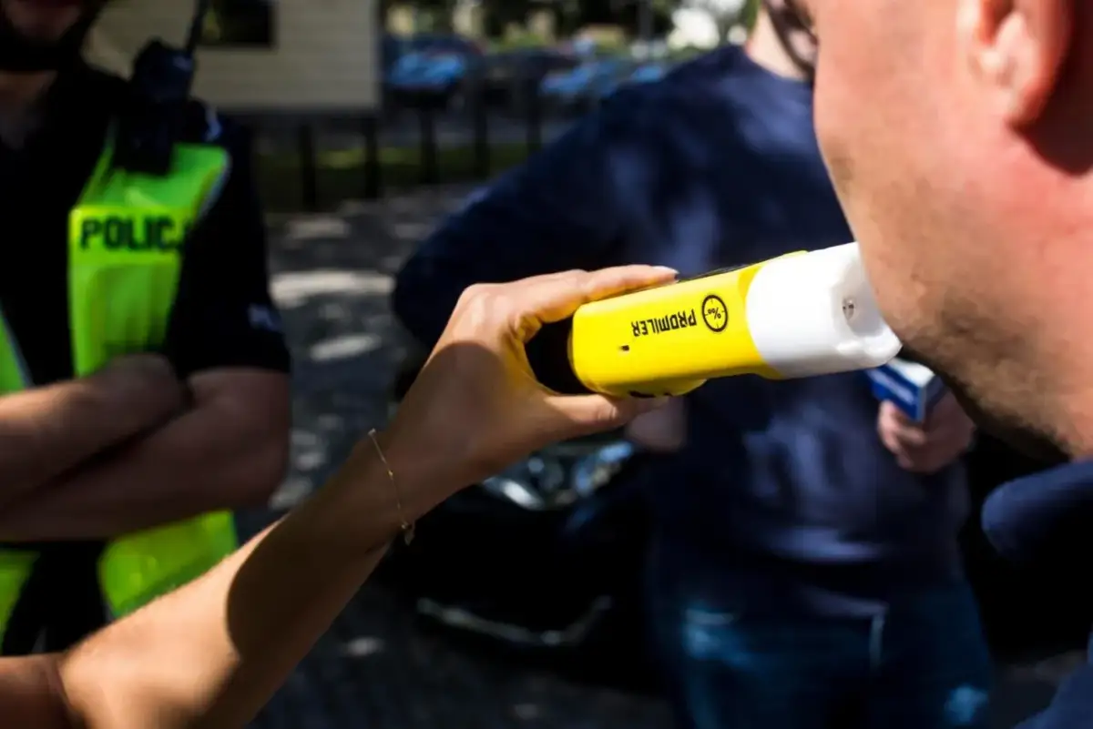 Policjant bada pracownika alkomatem.