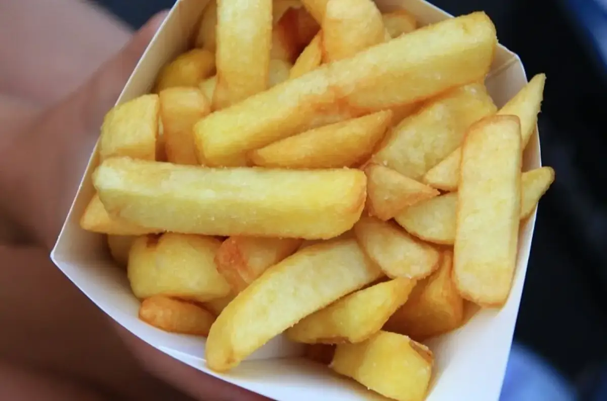 Złociste, grube frytki belgijskie w papierowym rożku.