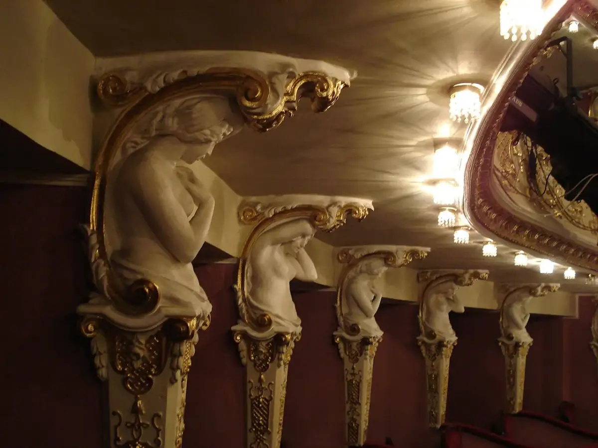 Rząd białych, zdobionych złotem kariatyda wspiera sufit teatru.
