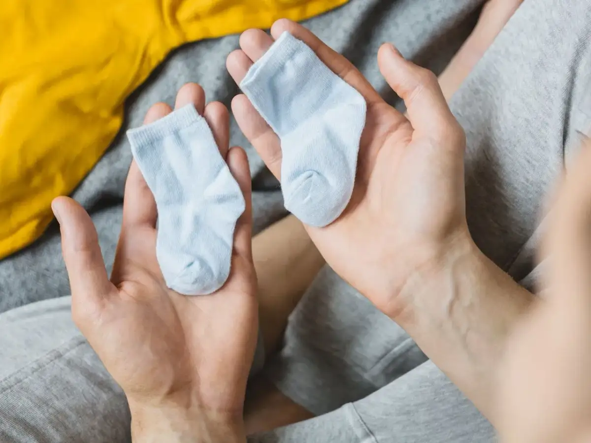 Dwie maleńkie, błękitne skarpetki w dłoniach. Zastanawiasz się, jaki rozmiar skarpetek dla noworodka będzie najlepszy?