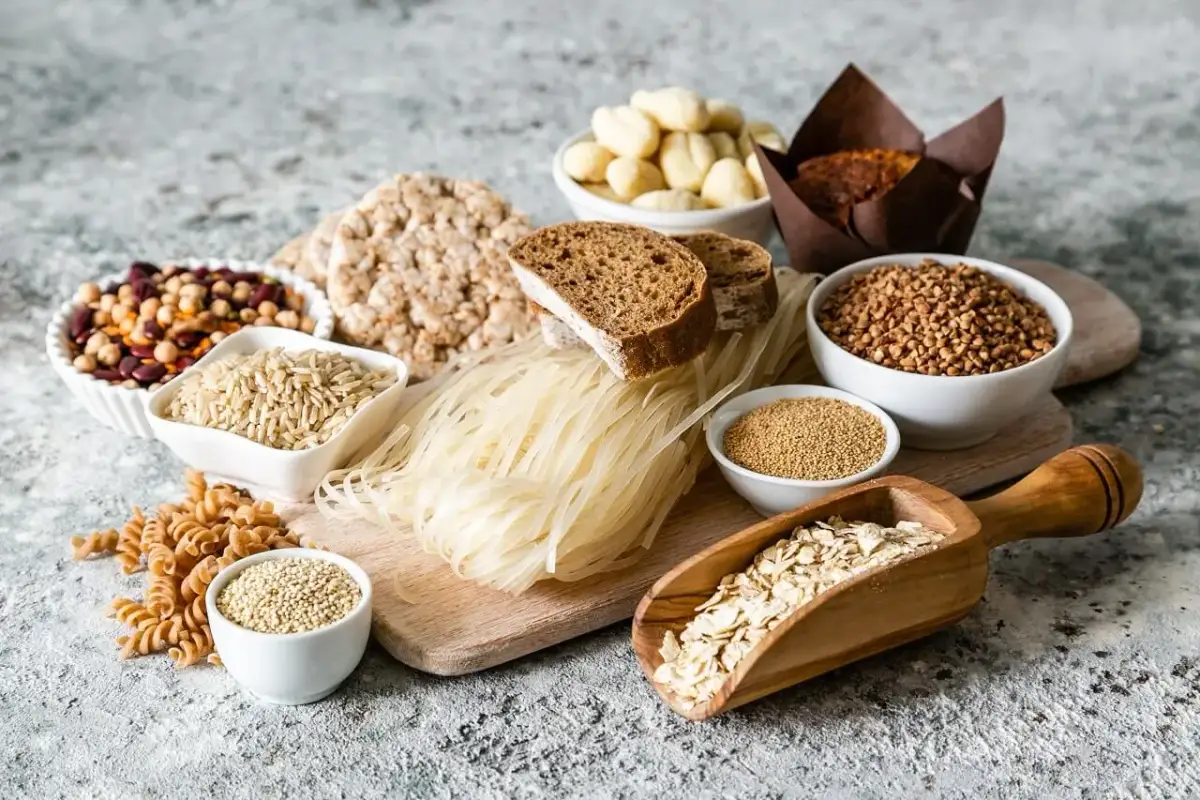 Różnorodne produkty spożywcze, w tym ryż, makaron, pieczywo, kasza, płatki owsiane i nasiona.