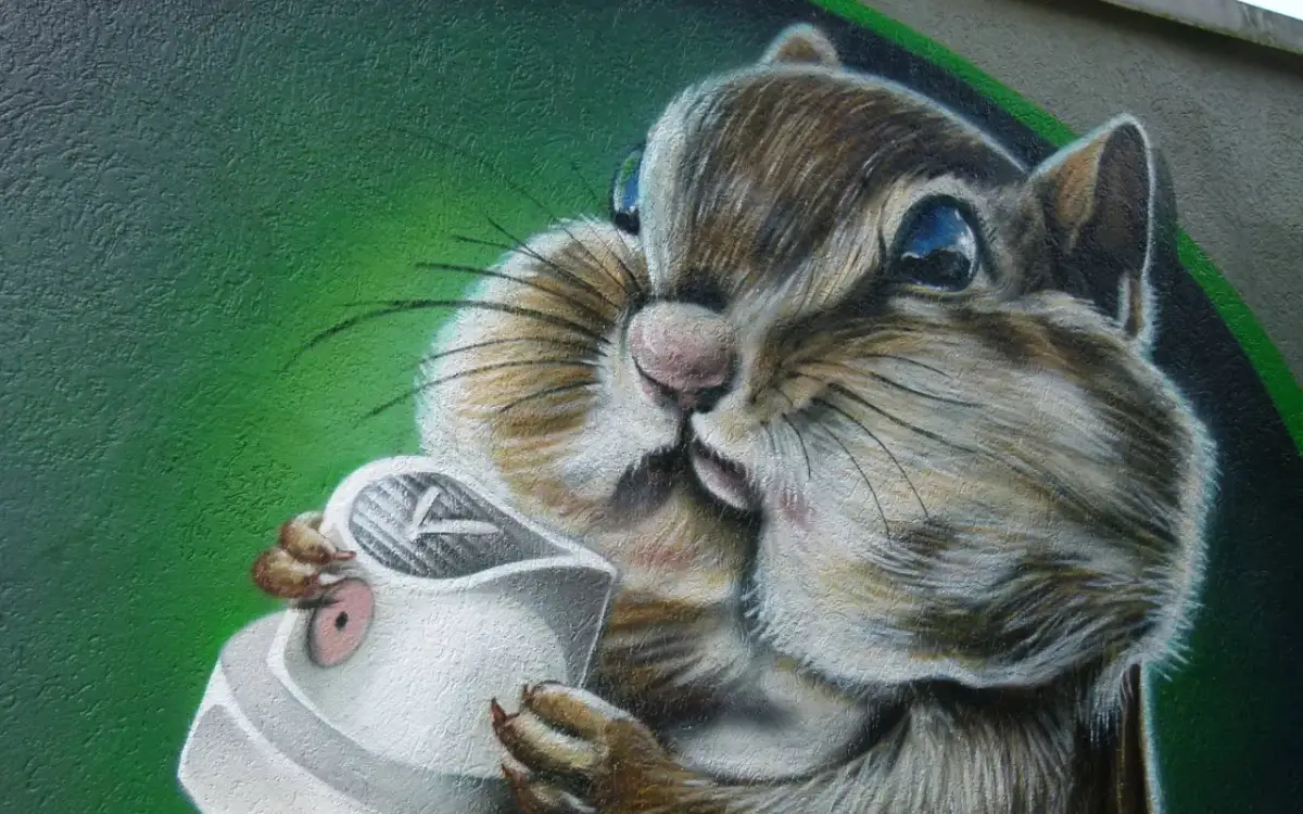 Graffiti eines Eichhörnchens, das eine Spraydose hält, vor grünem Hintergrund.