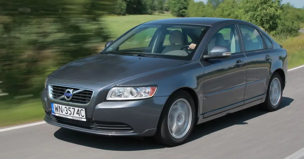 Szary Volvo S40 2.0 diesel w ruchu, z rozmytym tłem zieleni i drogi.