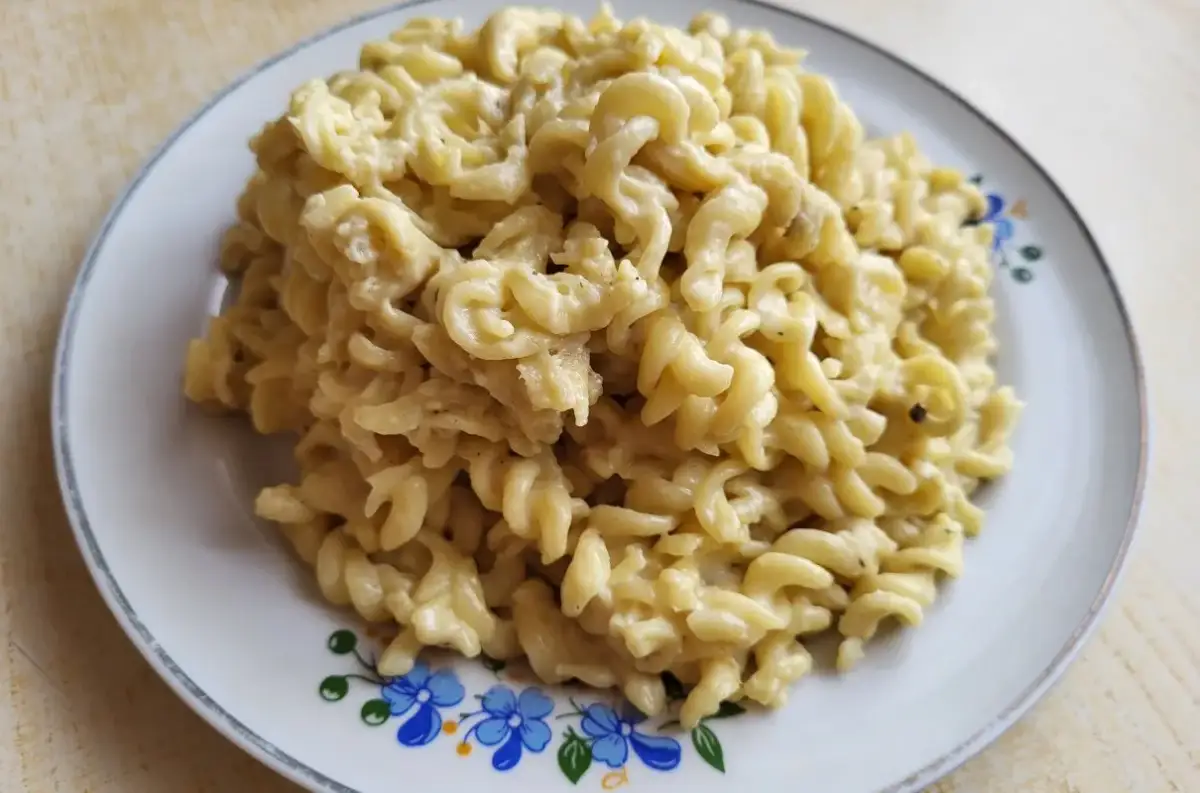 Pyszny makaron fusilli w kremowym sosie pieczarkowym, podany na talerzu z niebieskimi kwiatami.