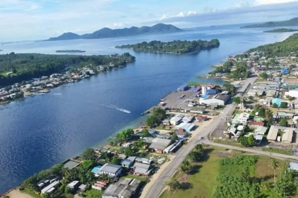 Widok na zatokę z miasteczkiem na wybrzeżu, portem i łodzią. W oddali wyspy i góry. Bougainville.