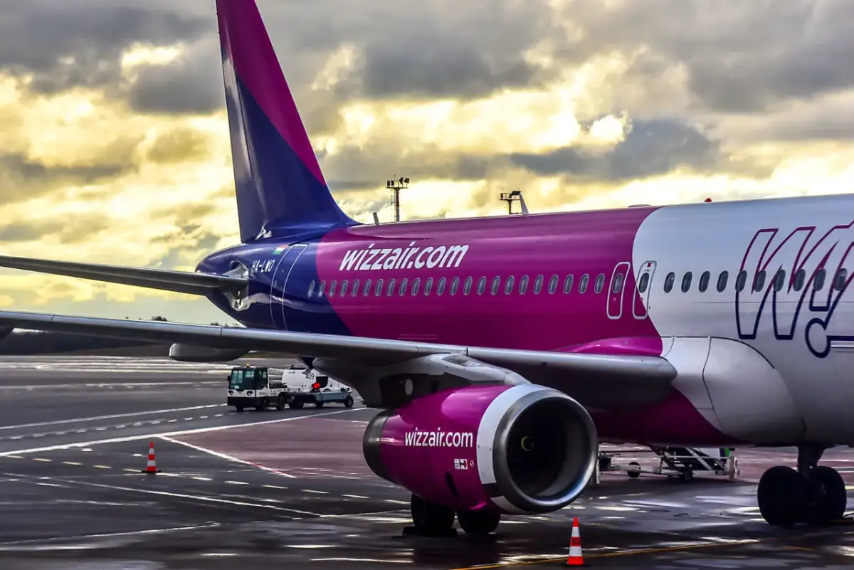 Samolot Wizz Air na płycie lotniska pod pochmurnym niebem.