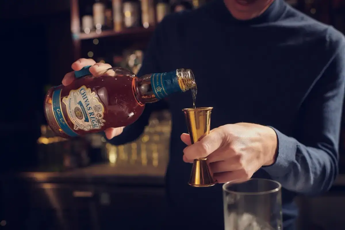 Barman nalewa Chivas Regal do miarki. Czy whisky zawiera cukier? To pytanie zadaje sobie wielu miłośników tego trunku.