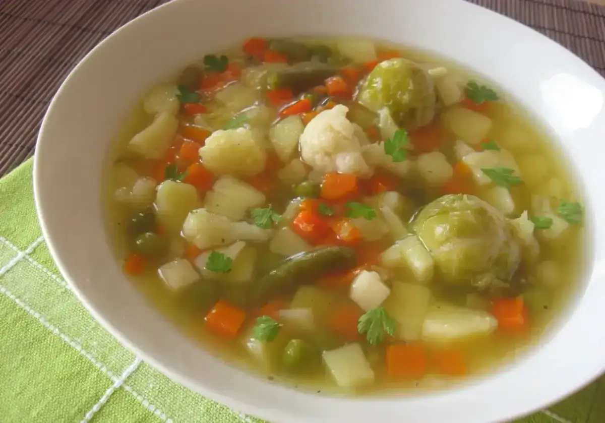Aromaticzna jarzynowa zupa z ziemniakami, marchewką, kalafiorem i brukselką, udekorowana natką pietruszki.