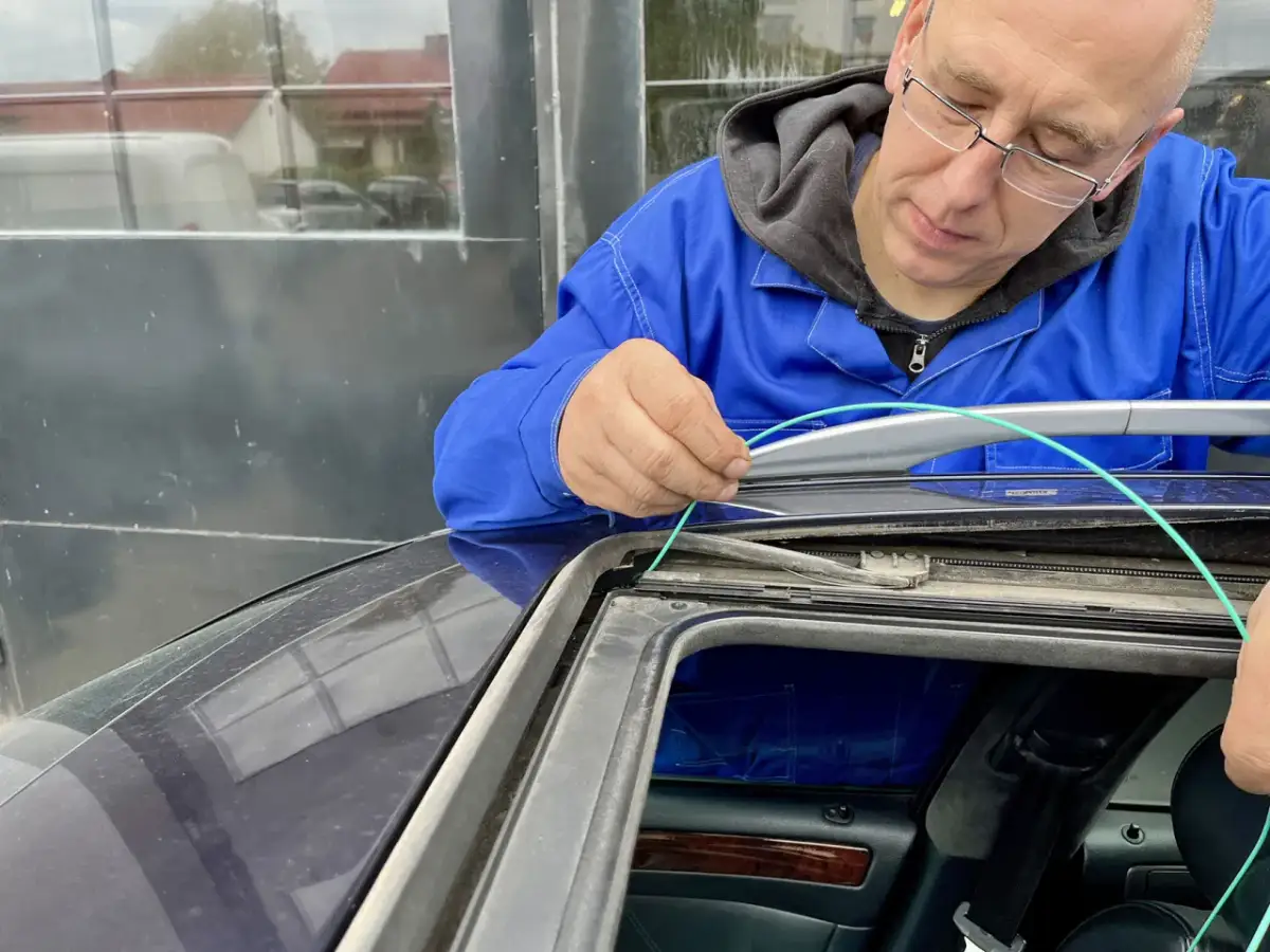 Mechanik czyści przewody odpływowe w samochodzie, aby zapobiec gromadzeniu się wody.